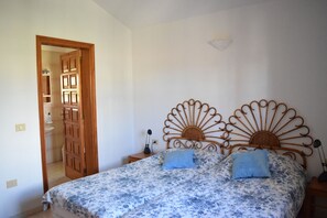 Une chambre à coucher avec un lit, deux tables de chevet, une porte en bois et un luminaire fixé au mur.