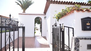 A white building with a tiled roof, a metal gate, and a palm tree. - House / Villa with private pool (San Miguel de Abona)