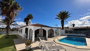 A villa with a swimming pool, outdoor seating, and palm trees. - House / Villa with private pool (San Miguel de Abona)
