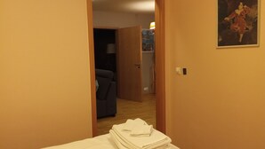 A hotel room with a bed, a door leading to another room, and a framed picture on the wall.