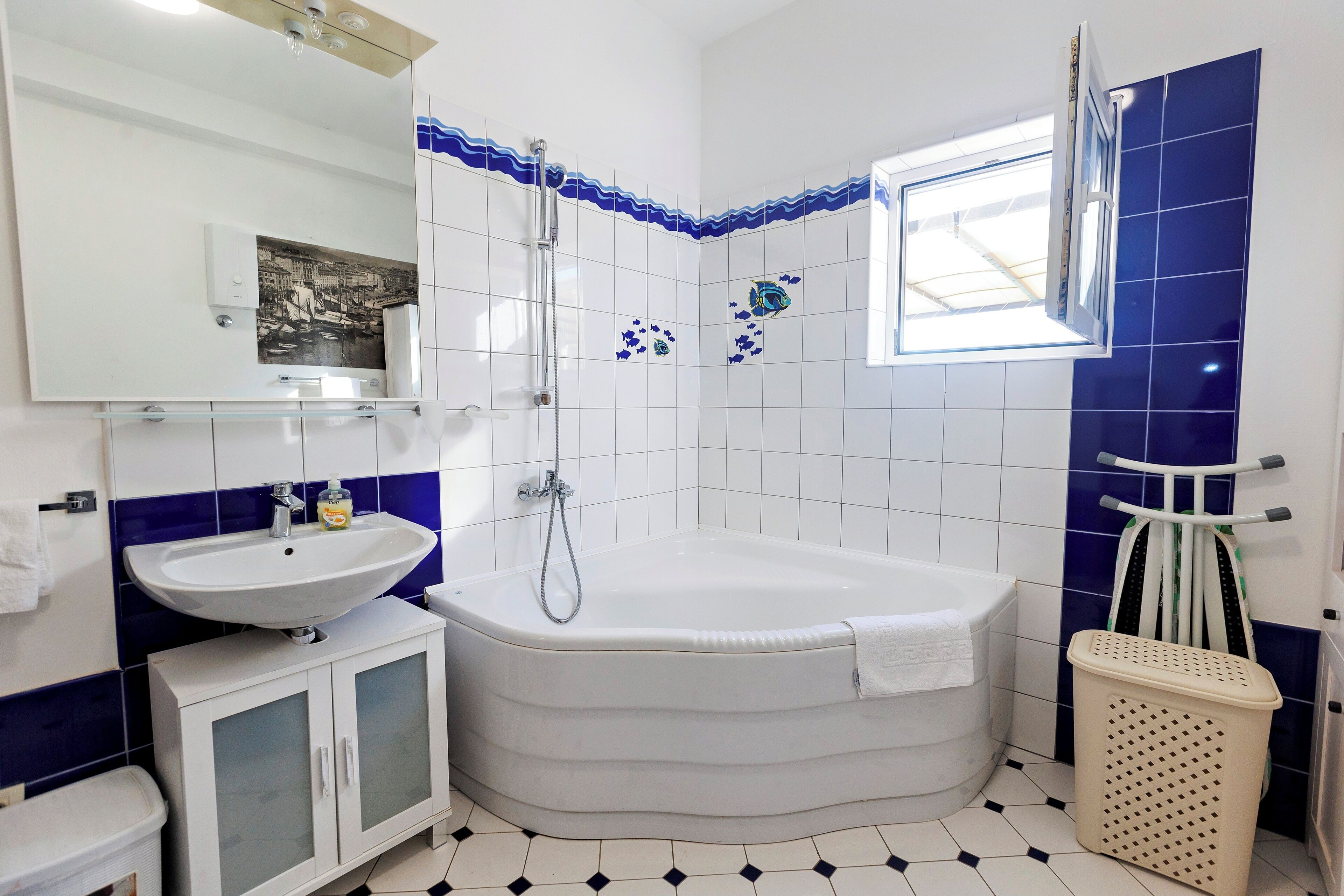 A bathroom with a bathtub, a sink, a mirror, and a window.