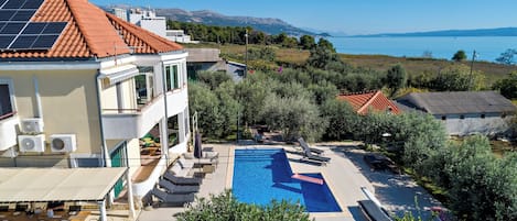 A residential property with a swimming pool, outdoor seating, and a view of the sea.
