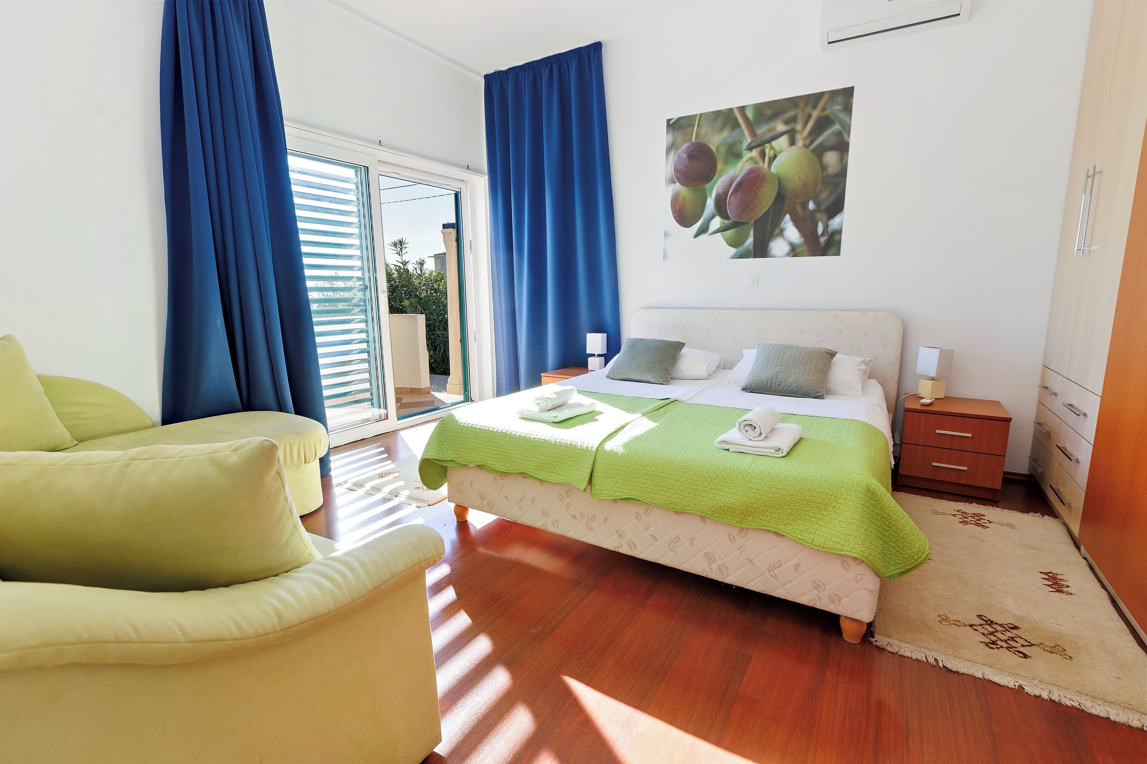 A bedroom with a bed, a chair, a nightstand, and a window with curtains.