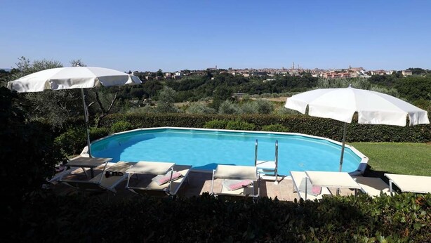 A rectangular swimming pool with white umbrellas and lounge chairs. - Villa with unique view of Siena with private pool (Ascarello)