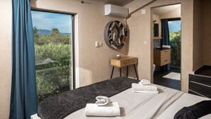 A modern hotel room with a large window, a round mirror, a wooden bedside table, and a neatly made bed with towels. - Eclectic Villa with Swimming Pool set in it's own Olive Grove (Stari Grad)