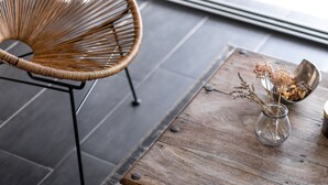 A wicker chair, a wooden table with a vase of dried flowers, and a rug on a dark floor. - Eclectic Villa with Swimming Pool set in it's own Olive Grove (Stari Grad)