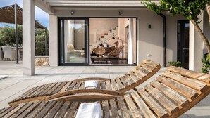 A wooden lounge chair with a towel, a glass door leading to a living area with a sofa and a chair, and a staircase inside. - Eclectic Villa with Swimming Pool set in it's own Olive Grove (Stari Grad)