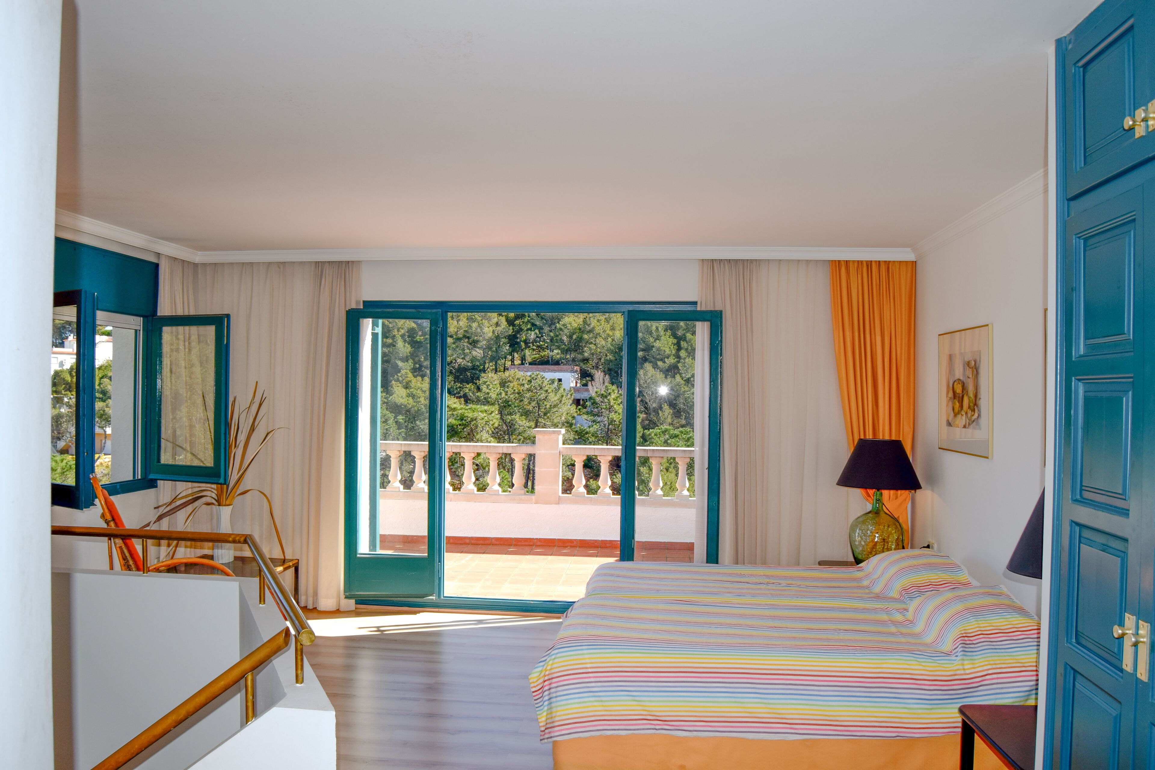Une chambre d’hôtel avec un lit, un balcon donnant sur un beau paysage et une porte.