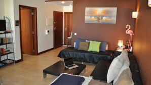 A living room with a bed, a coffee table, a bookshelf, and a painting on the wall. -  Apartment sea view in Salgados Village (Guia)