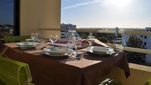 A dining table set for two with plates, cutlery, and wine glasses, overlooking a cityscape. -  Apartment sea view in Salgados Village (Guia)