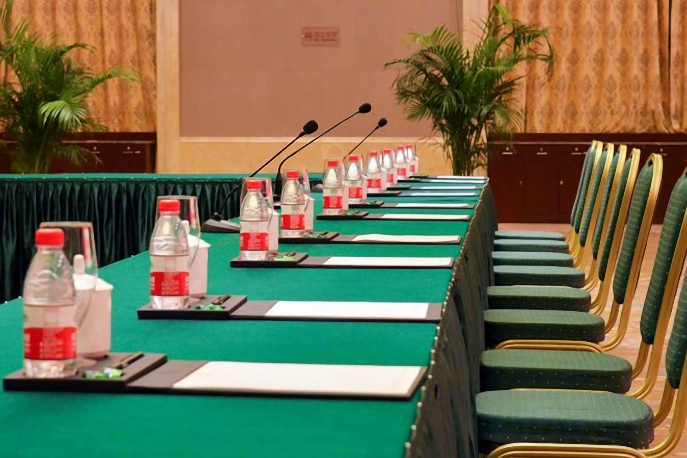 A conference room with a long table, chairs, microphones, water bottles, and nameplates.