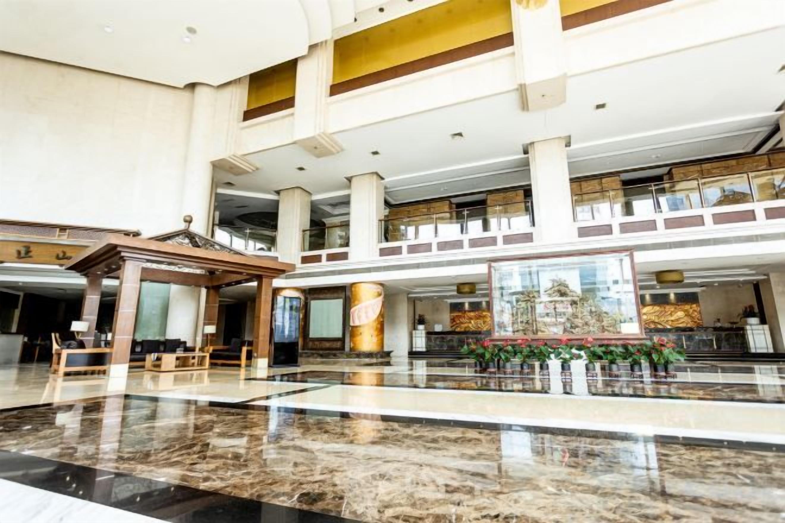 A spacious lobby with a high ceiling, marble flooring, and a central seating area.
