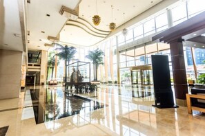 A spacious lobby with a reflective floor, a fountain, and palm trees. - Jinling Danyang Hotel (Danyang)
