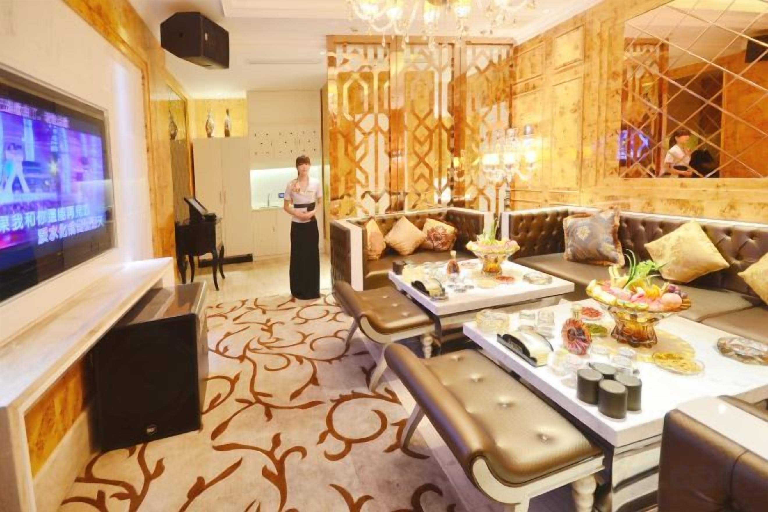 A spacious living room with a large flat-screen TV, comfortable seating, and a decorative chandelier.