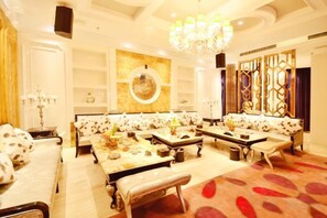 A spacious lounge area with sofas and tables, a chandelier, and decorative wall panels. - Jinling Danyang Hotel (Danyang)