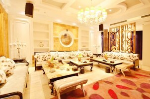 A spacious lounge area with sofas and tables, a chandelier, and decorative wall panels.