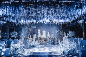 A circular seating arrangement with a central stage, surrounded by chairs, and a backdrop with a castle-like structure. - Jinling Danyang Hotel (Danyang)