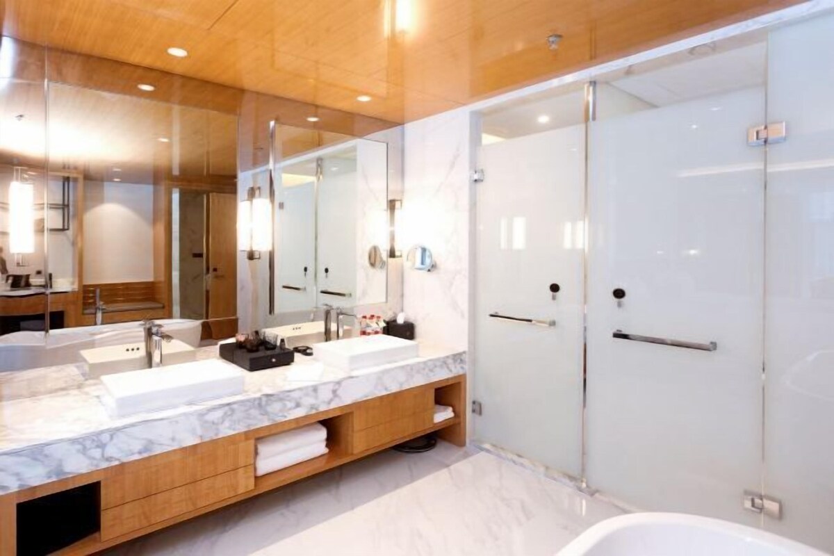A modern bathroom with two sinks, a large mirror, and a walk-in shower.