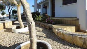A building with a white exterior, a covered porch, and a gravel pathway. - House with garden (Albufeira)
