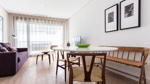 A modern living room with a round dining table, wooden bench, and a sofa. - Puerta del Sol by Home at Homes (Sevilla)