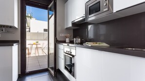 A modern kitchen with white cabinets, a built-in oven, and a microwave. - Puerta del Sol by Home at Homes (Sevilla)