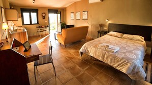 Une chambre d’hôtel comprenant un lit, un bureau avec un ordinateur portable, un canapé et un coin repas avec une table et des chaises.