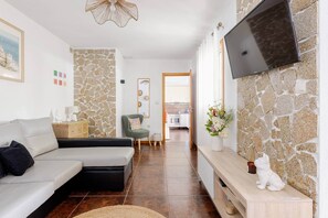 Una sala de estar moderna con un sofá, un televisor montado en la pared y una pared de piedra.