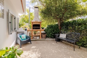 A patio with a brick-built outdoor oven, a bench, and a chair with a cushion. - Casa do Fontanário (Penafiel)