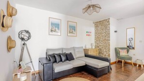 A modern living room with a grey sectional sofa, a stone accent wall, and a green armchair.
