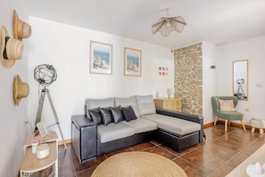 A modern living room with a grey sectional sofa, a stone accent wall, and a green armchair. - Casa do Fontanário (Penafiel)