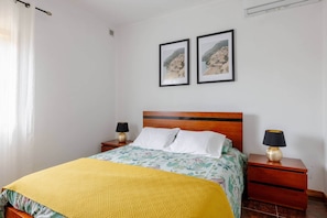 A hotel room with a bed, two nightstands, a wooden headboard, and two framed pictures on the wall. - Casa do Fontanário (Penafiel)