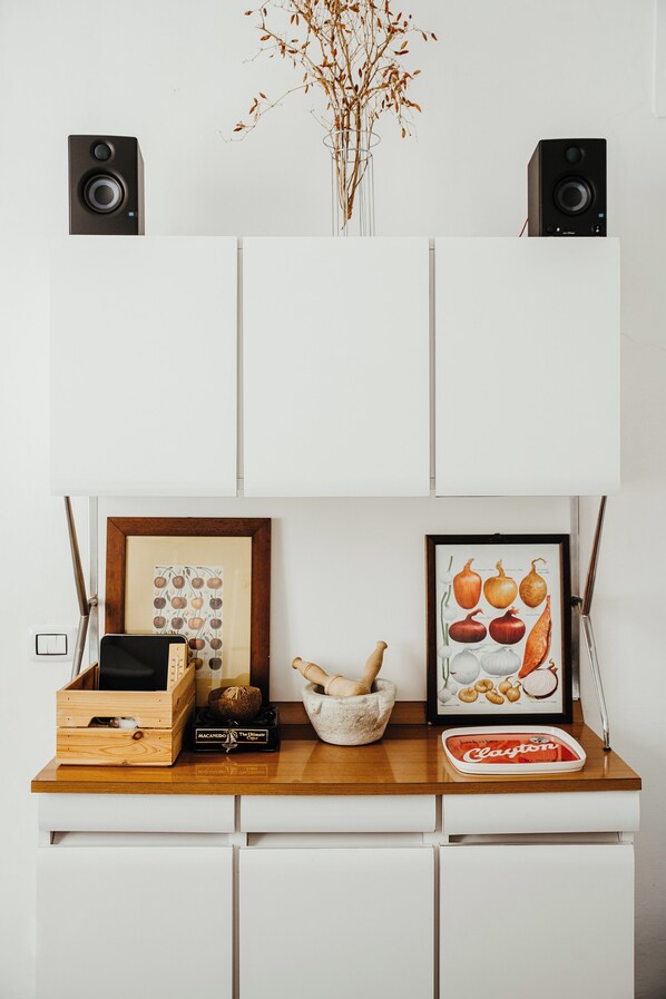 A kitchen counter with a wooden box, a framed picture of fruits, a bowl, and a bottle.