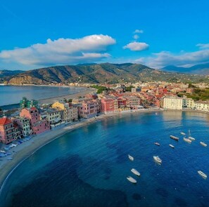 A coastal town with colorful buildings, a beach, and boats in the water.