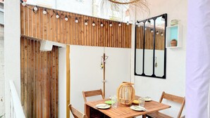 A wooden table set for two with chairs, a hanging light fixture, and a wall-mounted mirror.
