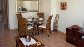 Un comedor con una mesa redonda, sillas de mimbre y un espejo grande colgando sobre ella.
