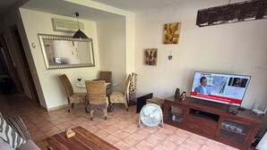 Una sala de estar con un sofá, una mesa de centro de madera, un televisor y un ventilador.