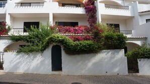A white building with balconies, satellite dishes, and a gate.