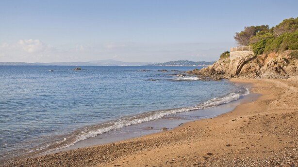 A beach with pebbles, a stone building with a balcony, and a clear blue sea. - 4 bed sleeps 8  beach front villa with Shared Pool and Private Garden. (Roquebrune-Sur-Argens)