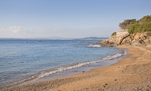 A beach with a rocky shoreline and a building on the cliff. - 4 bed sleeps 8  beach front villa with Shared Pool and Private Garden. (Roquebrune-Sur-Argens)