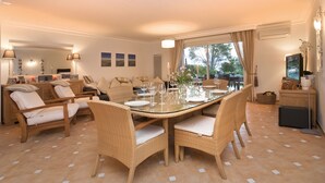 A dining area with a glass-top table set for six, surrounded by wicker chairs with white cushions. - 4 bed sleeps 8  beach front villa with Shared Pool and Private Garden. (Roquebrune-Sur-Argens)