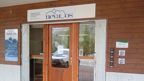 A wooden building with a sign reading "nevaDos" and a contact number. - Magic Pirineos, Apartment in Linsoles, Valle de Benasque with Pool and WIFI  (Anciles)