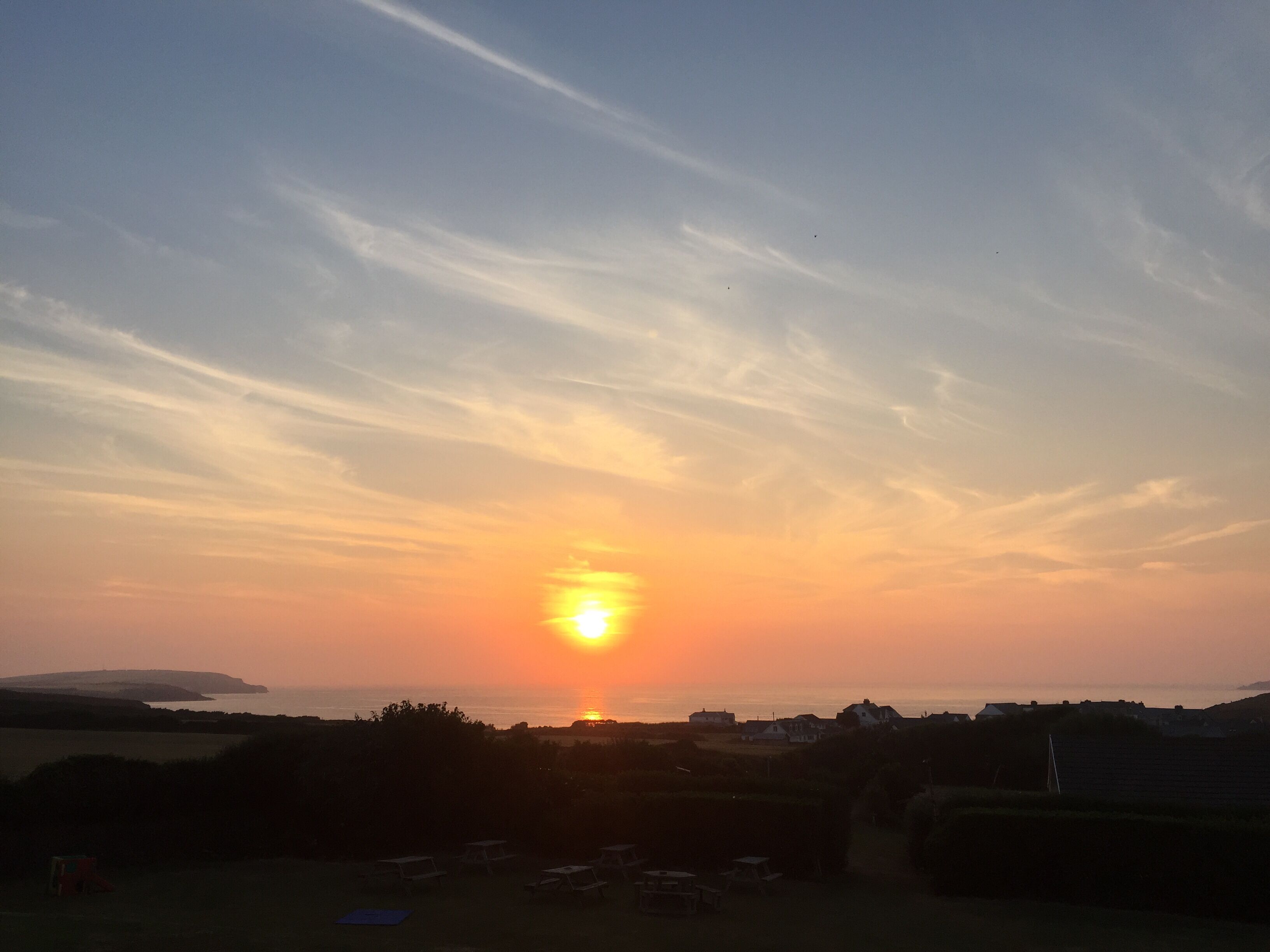 A sunset over a rural landscape with fields and a few houses.