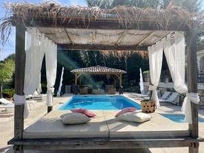 A pool area with a pergola, lounge chairs, and a gazebo in the background.