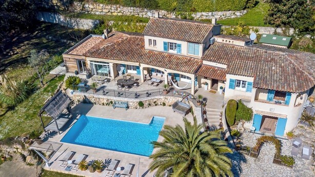 Un'ampia casa con piscina, area salotto esterna e un muro in pietra.
