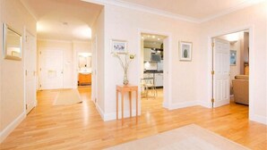 A spacious living area with hardwood flooring, a dining table, and chairs. There is a kitchen visible in the background with modern appliances. - Spacious and luxurious, Barnton - Cramond, Edinburgh - near golf, city, sea  (Edinburgh)
