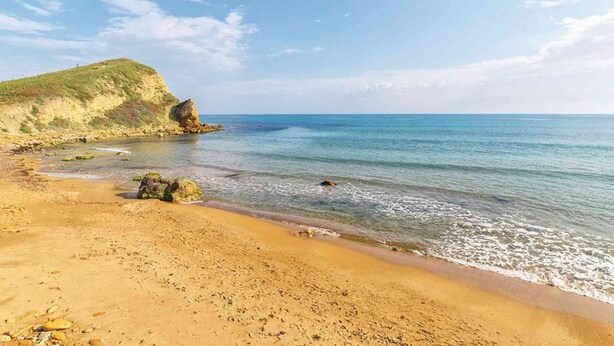 A sandy beach with a rocky outcrop and calm sea. - Holiday Home Sciacca (San Giorgio)