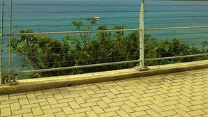 A coastal view with a clear sky, a metal railing, and a paved walkway. - Sanremo, apartment with parking, air conditioning, near the beaches (Sanremo)
