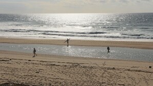 Une plage où trois personnes se promènent le long du rivage.
