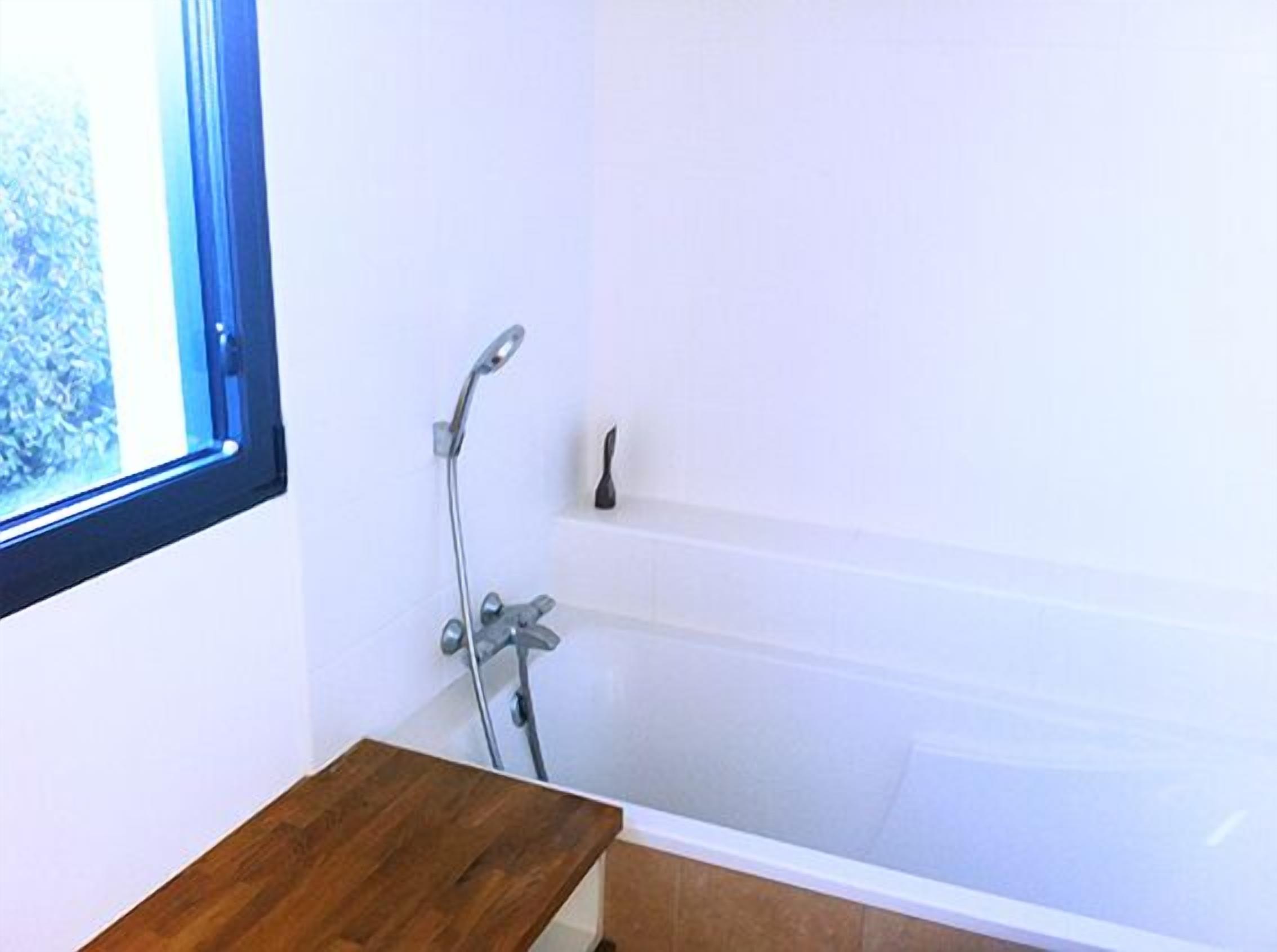 Ein Badezimmer mit Badewanne, Dusche und Fenster.