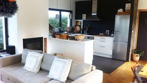 Una sala de estar moderna con un sofá y una cocina al fondo.